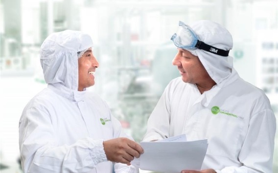 Dos trabajadores de la planta de Grünenthal mirándose, sonriendo y sosteniendo una hoja de papel en las manos
