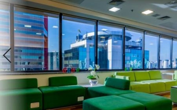 Sala de descanso en oficina con sillones verdes y con vista a la calle