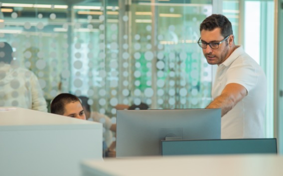 Hombre joven señalando la computadora y mujer joven mirando la computadora en un ambiente de oficina